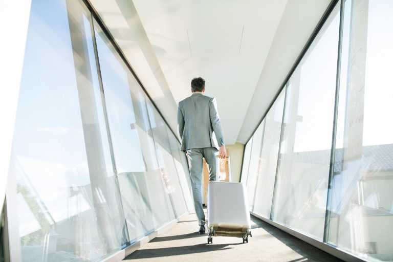 Mature businessman with suitcase travelling.